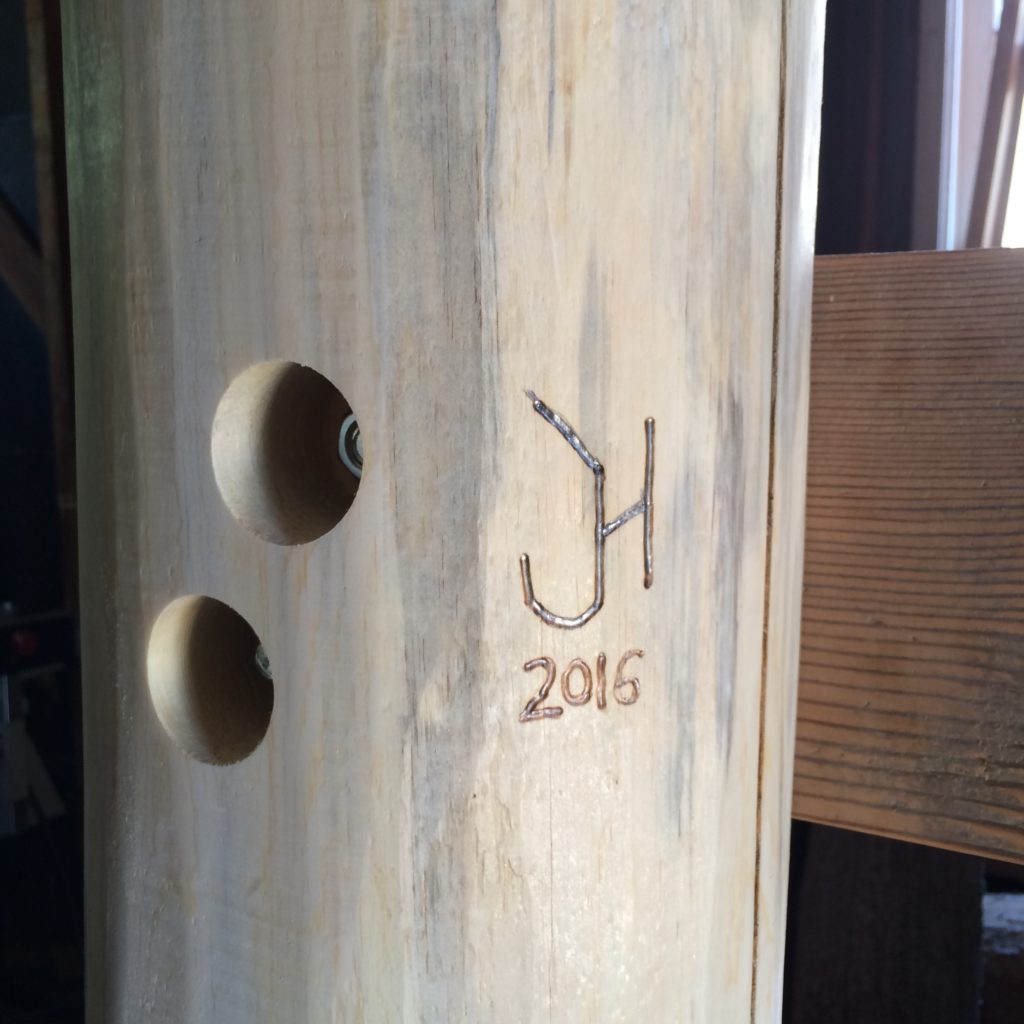 Henningsen Woodshop's brand, with year of creation, on a bed post